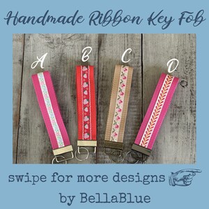 May include: Four handmade ribbon key fobs with different designs. The key fobs are labeled A, B, C, and D. The key fobs have various patterns, including floral, hearts, and geometric designs. The text "Handmade Ribbon Key Fob" is at the top.