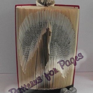 May include: A book folded into the shape of a bird with a paper flower on top. The book is red and the flower is white with a brown center. The book is titled "Patterns for Pages".