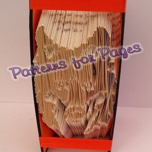 May include: A handmade book art piece with pages folded to create a mountain-like design. The book is encased in a black and orange frame with a red ribbon. The text "Patterns for Pages" is visible.