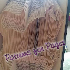 Könnte beinhalten: Ein Buch mit Seiten, die zu einem dreidimensionalen Muster gefaltet sind, das einer Blume ähnelt. Das Buch ist geöffnet und die gefalteten Seiten sind sichtbar. Der Text "Patterns for Pages" ist in Pink auf den gefalteten Seiten geschrieben.