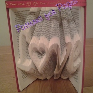 Op de afbeelding: Een boek met pagina's gevouwen in de vorm van het woord "love" met een rode kaft en de woorden "True Love" en "Patterns for Pages" op de voorkant.