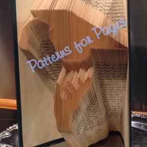 May include: A book with pages folded into a 3D shape, resembling a bird. The book is open and the folded pages are visible. The book is on a silver tray. The text "Patterns for Pages" is visible on the book.