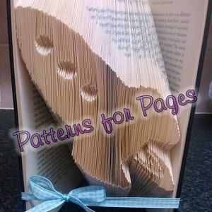 Könnte beinhalten: Ein Buch mit Seiten, die zu einer Rakete gefaltet sind. Das Buch steht aufrecht auf einem Tisch. Ein hellblaues Band ist um das Buch gebunden. Der Text "Patterns for Pages" ist auf dem Buch sichtbar.