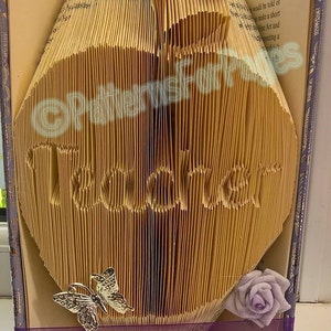 May include: A book with the word "Thank You" folded into the pages. The book is decorated with two silver butterflies and a purple rose.