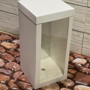 May include: White cardboard box with a clear plastic window on the front. The box has a hole in the bottom.