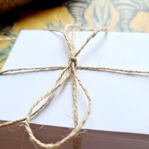 May include: A stack of white paper cards tied together with natural twine.