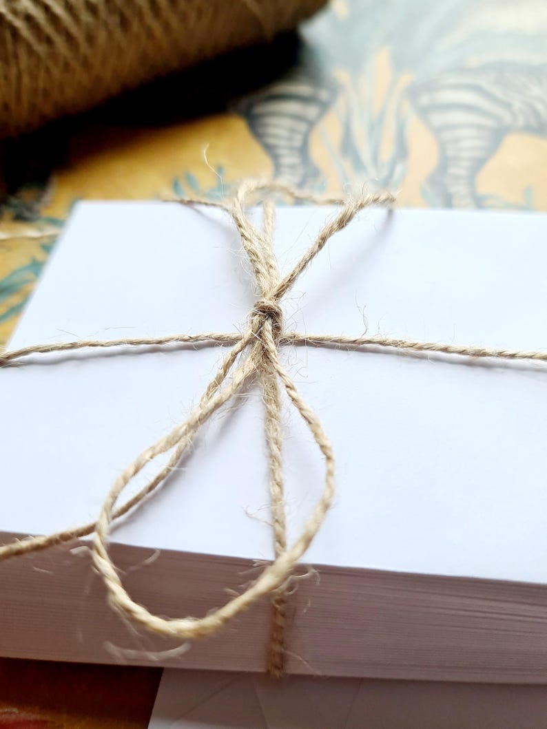 May include: A stack of white paper cards tied together with natural twine.