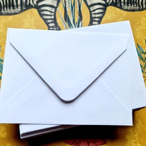 May include: A stack of white envelopes with a pointed flap. The envelopes are blank and ready to be used for sending letters or cards.