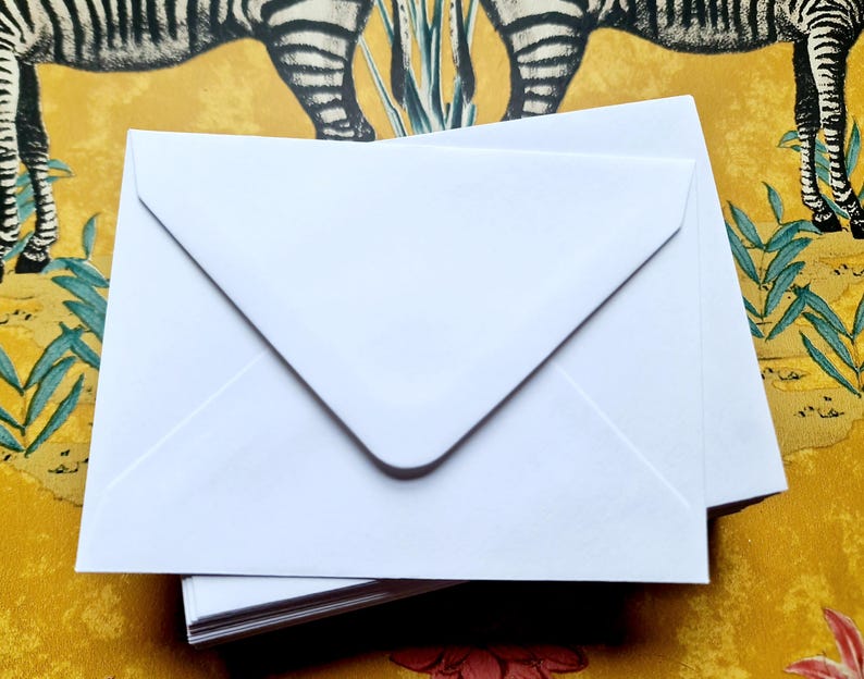 May include: A stack of white envelopes with a pointed flap. The envelopes are blank and ready to be used for sending letters or cards.