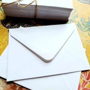 May include: A stack of white envelopes tied together with twine. The envelopes are on a colorful patterned surface.