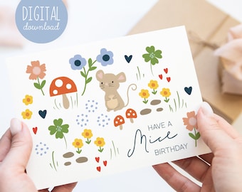 May include: A white card with a cute mouse illustration surrounded by flowers, mushrooms, and hearts. The text "Have a Mice Birthday" is written in cursive on the card.