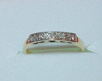 May include: A gold band ring with a row of small diamonds set in the center.