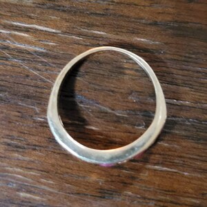 May include: A gold band ring with three small pink stones set in the band.