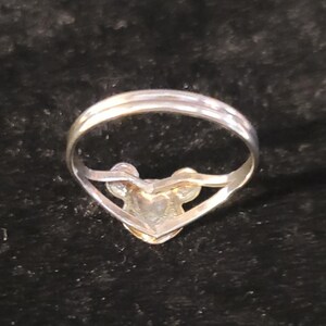 Puede incluir: Un anillo de tono plateado que presenta un dise&ntilde;o central con forma de cabeza de rat&oacute;n estilizada, con dos orejas circulares y una cara redondeada. La banda es delgada y met&aacute;lica, conect&aacute;ndose a la base del adorno en la parte frontal.