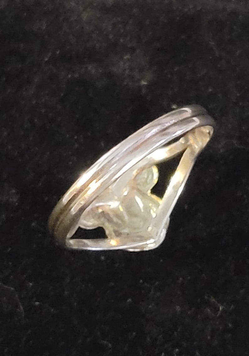 Puede incluir: Un anillo de metal plateado con un dise&ntilde;o de v&aacute;stago dividido que converge en la parte frontal. La banda tiene un acabado liso y pulido con una silueta en forma de V, con un espacio central abierto entre las dos bandas que se unen en un punto.