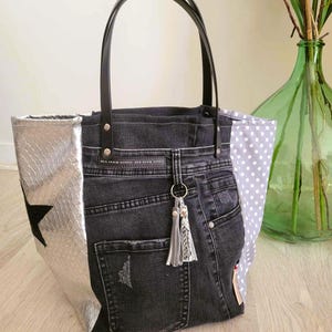 Peut inclure: Un sac cabas en denim noir avec une étoile argentée et un tissu à pois. Le sac a une anse en cuir noir et un charme en forme de pompon.