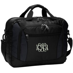 May include: A black laptop briefcase featuring a front zippered pocket, dual top handles, and a detachable shoulder strap. The front panel displays an embroidered white monogram with the letters KSA in a decorative, interlocking script font style.