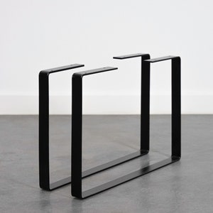 Peut inclure: Deux pieds de table en métal noir de forme rectangulaire. Les pieds sont en métal robuste et ont un design simple et moderne.