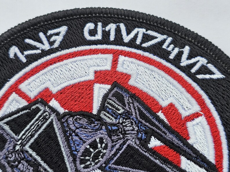 May include: Black and red embroidered patch with a TIE fighter silhouette and the text "TIE/IN" in white.