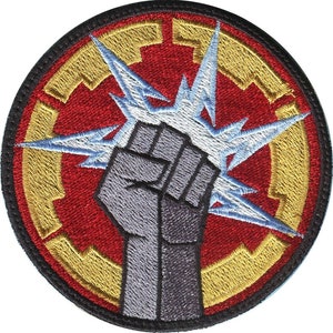 May include: A red, gold, and white embroidered patch with a raised fist and a lightning bolt. The fist is clenched and the lightning bolt is coming out of the fist. The patch is circular and has a black border.