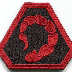 May include: A red embroidered scorpion symbol on a black hexagonal patch with a red border.