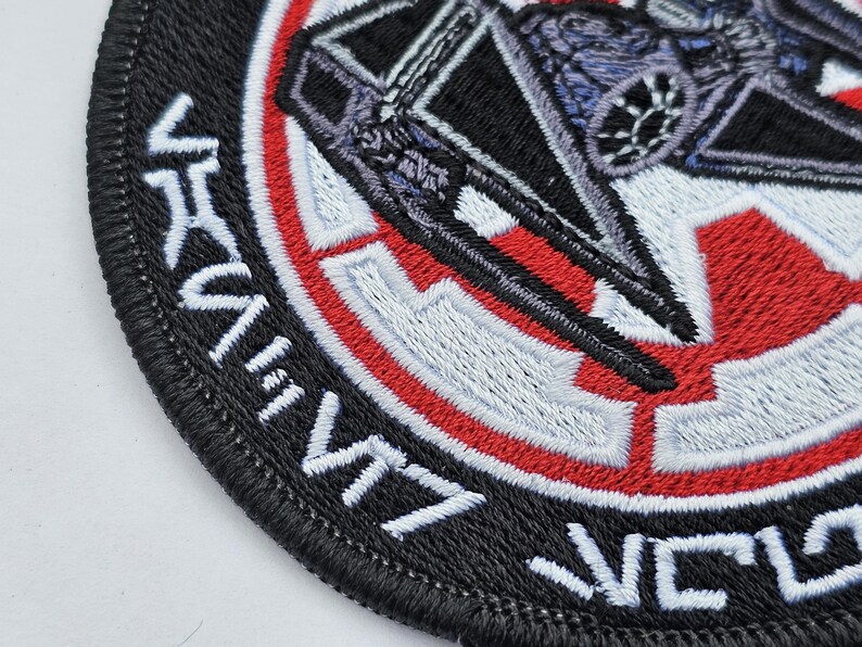 May include: Black and white embroidered patch with a red and white circle in the center. The circle features a stylized image of a spaceship. The text "VICTORY" is embroidered around the outside of the circle.