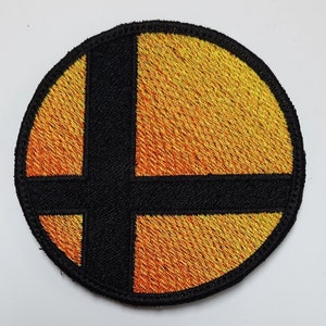 Puede incluir: Un parche redondo bordado en negro y naranja con el logotipo de Super Smash Bros.