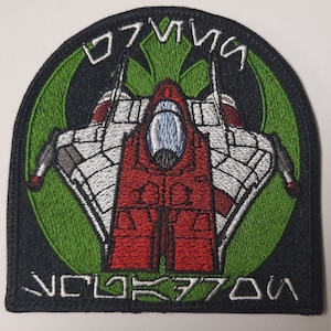 May include: A black and green embroidered patch featuring a spaceship with the text "07 VII" and "VCL0K3770N".