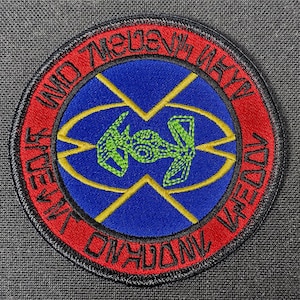 May include: A red, black, and blue embroidered patch with a stylized spaceship design and the text "UNITED 7TH FLEET NAVY 1997".