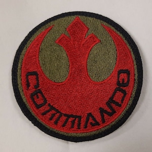 May include: A red embroidered Rebel Alliance symbol with the word "COMMAND" written around it in black. The symbol is on a green background with a black border.