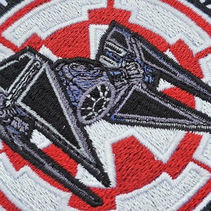May include: A black and gray TIE fighter embroidered patch with a red and white Rebel Alliance symbol in the background.