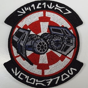 May include: A black and white embroidered patch with a red and white Imperial symbol from Star Wars. The patch features a TIE fighter with the text "TIE/ln" and "VNX-11V" in white.