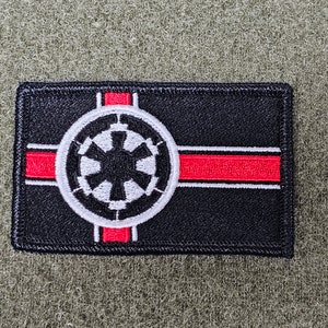 May include: A black and red embroidered patch with the Imperial symbol from Star Wars. The symbol is white with a black center and is surrounded by a red stripe.