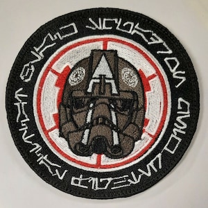May include: A black and white embroidered patch with a red circle in the centre. The circle features a white starburst design and a brown pilot helmet with a visor. The text around the circle reads "SKULL SQUADRON".