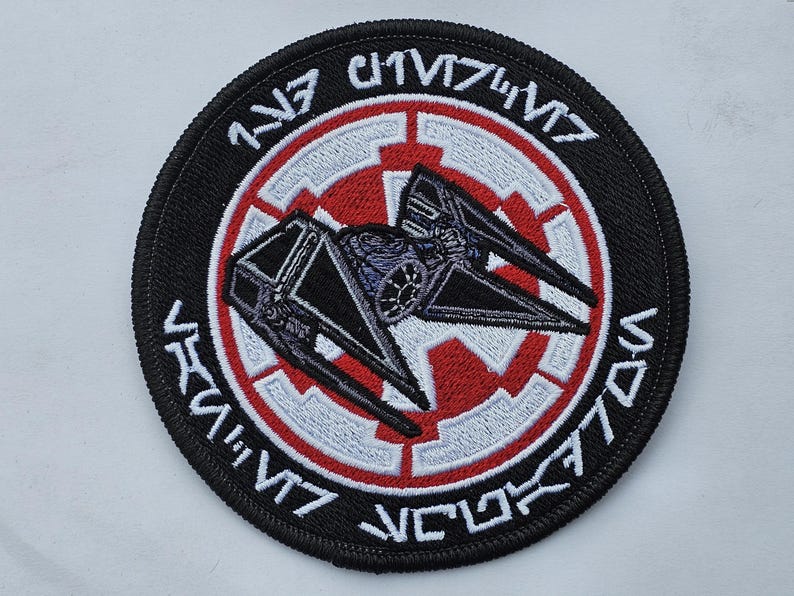 May include: Black and red embroidered patch with a TIE fighter silhouette and the text "1st TIE Fighter Squadron" in Aurebesh.
