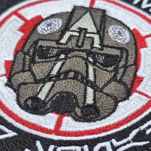 May include: A black and white embroidered patch with a red and white circle around a gray and white helmet design. The text "71st  Infantry Division" is embroidered around the outside of the patch.