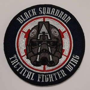 Op de afbeelding: Een geborduurde zwarte en witte patch met de tekst "Black Squadron Tactical Fighter Wing" in een cirkel. Het midden van de cirkel toont een gestileerd beeld van een pilotenhelm.