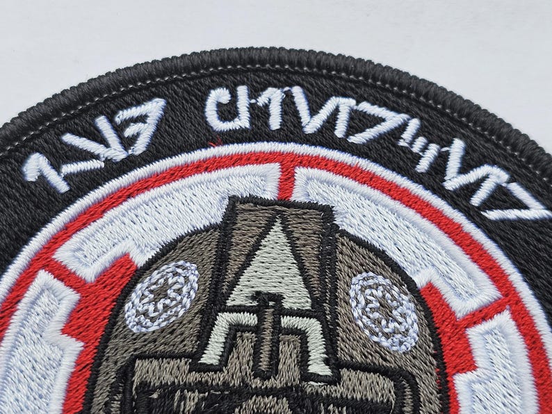 May include: A black and red embroidered patch with a stylized image of a helmet and the text "1/57th CHIMERA".