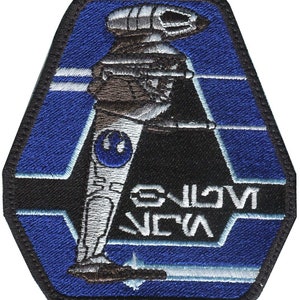 Peut inclure: Un écusson brodé bleu et noir représentant un vaisseau spatial blanc et gris avec le texte "GALACTIC  NEWA" en blanc.