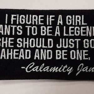 May include: Black embroidered patch with white text that reads "I figure if a girl wants to be a legend, she should just go ahead and be one, -Calamity Jane".
