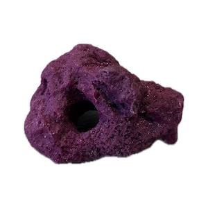 May include: A textured, purple aquarium decoration resembling a rock formation. The artificial rock has a large, circular opening and several smaller holes. The color is a deep, saturated purple.