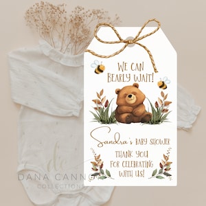 May include: A white thank you tag with a brown bear and bees. The text reads "We can bearly wait!" and "Sandra's Baby Shower Thank You for Celebrating with Us!"