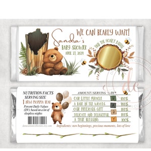 May include: A white chocolate bar wrapper with a brown bear illustration and the text "We can bearly wait!" and "Sandra's Baby Shower April 27, 2024". The wrapper also features a gold circle with the text "Find the Honey Barrel".