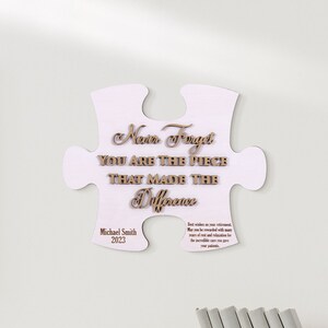 Peut inclure: Une pi&egrave;ce de puzzle en bois blanc avec le texte "Never Forget You Are The Piece That Made The Difference" et le nom "Michael Smith" et l'ann&eacute;e "2023".