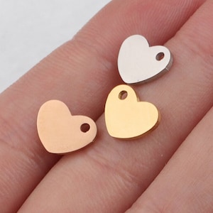 Puede incluir: Tres dijes de metal en forma de corazón en oro, plata y oro rosa. Cada dije tiene un pequeño agujero en la parte superior para sujetarlo a un collar o pulsera.