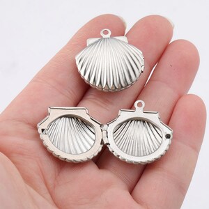 May include: Silver-toned seashell locket pendant with a hinged opening. The locket is detailed with a textured seashell design.
