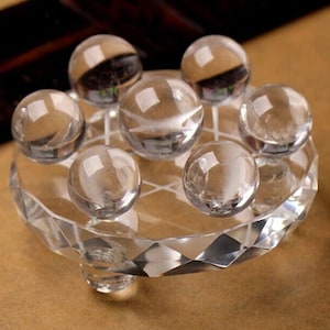 May include: A clear crystal base with seven clear crystal spheres on top. The base has a faceted design and three legs.