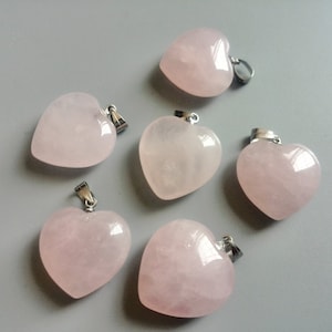 May include: Six pink heart-shaped pendants with silver metal bail loops. The pendants are made of rose quartz and are ready to be strung on a necklace or bracelet.