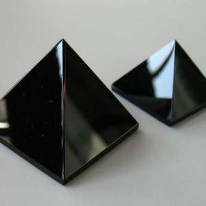 Puede incluir: Dos pirámides de obsidiana negra de diferentes tamaños. La pirámide más grande está en primer plano y la más pequeña está en el fondo.