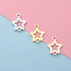 Pode incluir: Três pingentes de estrela de metal em prata, ouro e ouro rosa. As estrelas são abertas e têm um furo na parte superior para prender em joias.